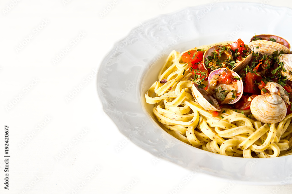 Italian tagliatelle in a restaurant with mussels and tomatoes. Dark background.
