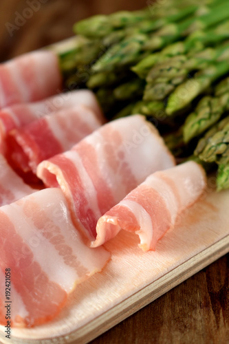 Bacon and green asparagus on a wooden board. Ingredients for cooking