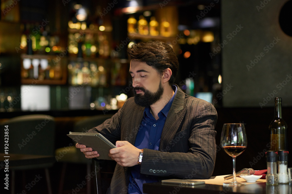 Man in restaurant reading news online Man in restaurant reading news online