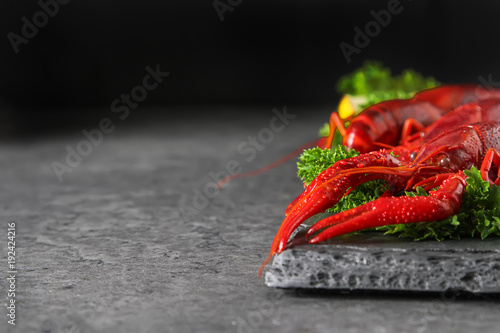 Delicious boiled crayfish close-up with lemon and parsley. Dark background. Dinner with seafood.