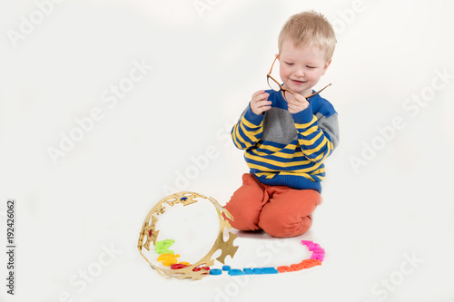 Happy charming Caucasian blond kid in colored clothes playing with plastic letters. Learning the alphabet, preparing for school. Education for kindergarten and preschool children. White background