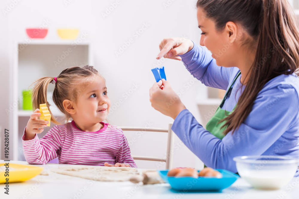 Happy mother and daughter are making cookies in their kitchen. Happy mother and daughter are making cookies in their kitchen.