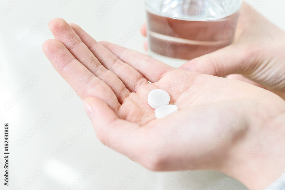 Concept image of treatment - hands of young woman with pills and water in close-up. Concept image of treatment - hands of young woman with pills and water in close-up.
