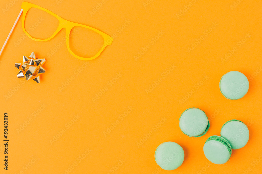 top view of party mask, bow and macarons isolated on orange, purim holiday concept top view of party mask, bow and macarons isolated on orange, purim holiday concept