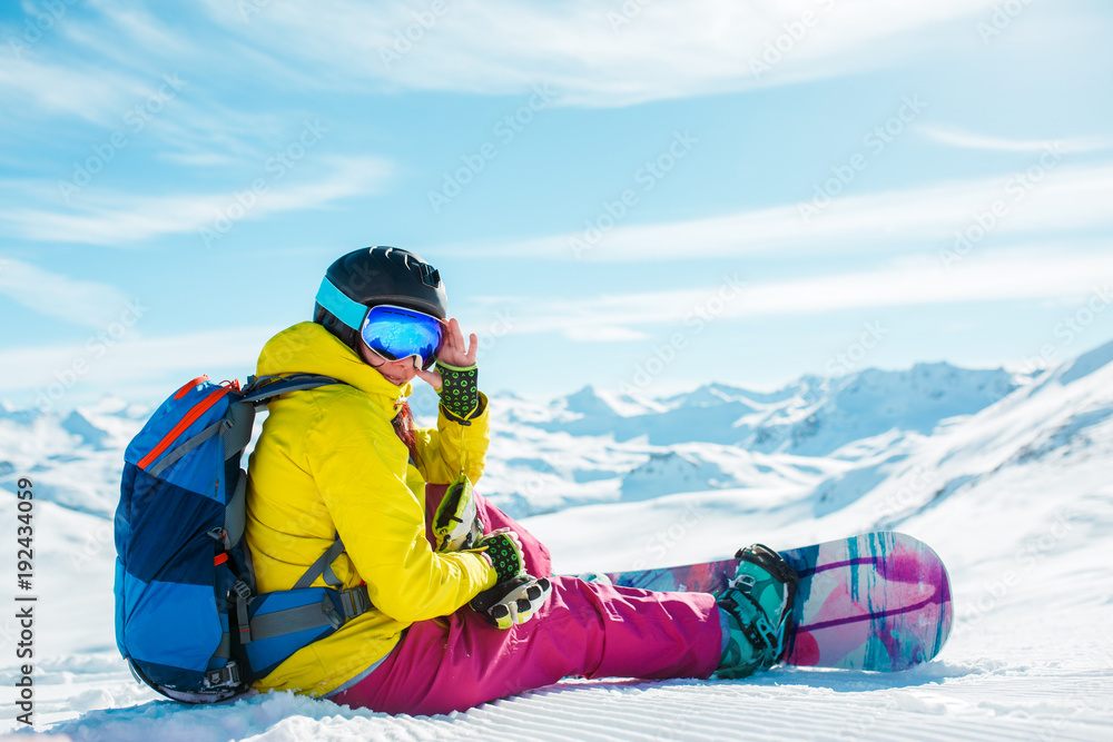Photo of woman in helmet with backpack sitting on snow with snowboard Photo of woman in helmet with backpack sitting on snow with snowboard