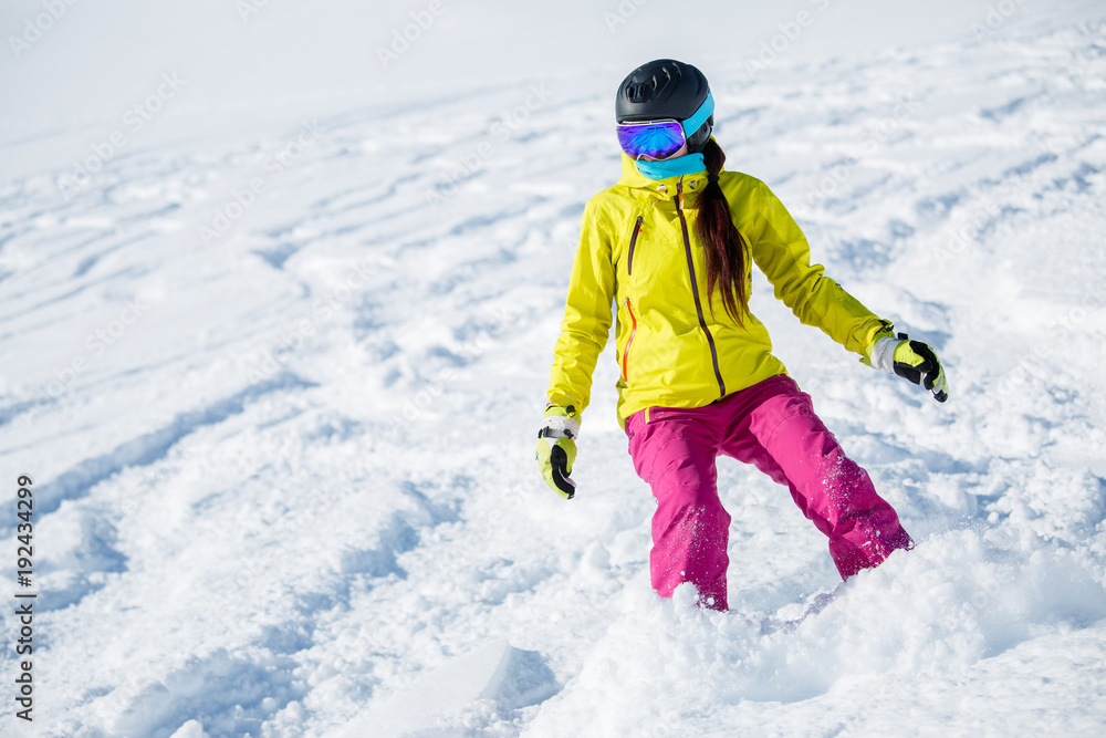 Picture of athlete girl in helmet and mask, snowboarding from snowy mountain slope Picture of athlete girl in helmet and mask, snowboarding from snowy mountain slope