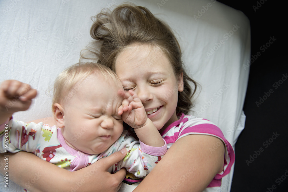 Girl lying down with her baby sister in Sweden Girl lying down with her baby sister in Sweden