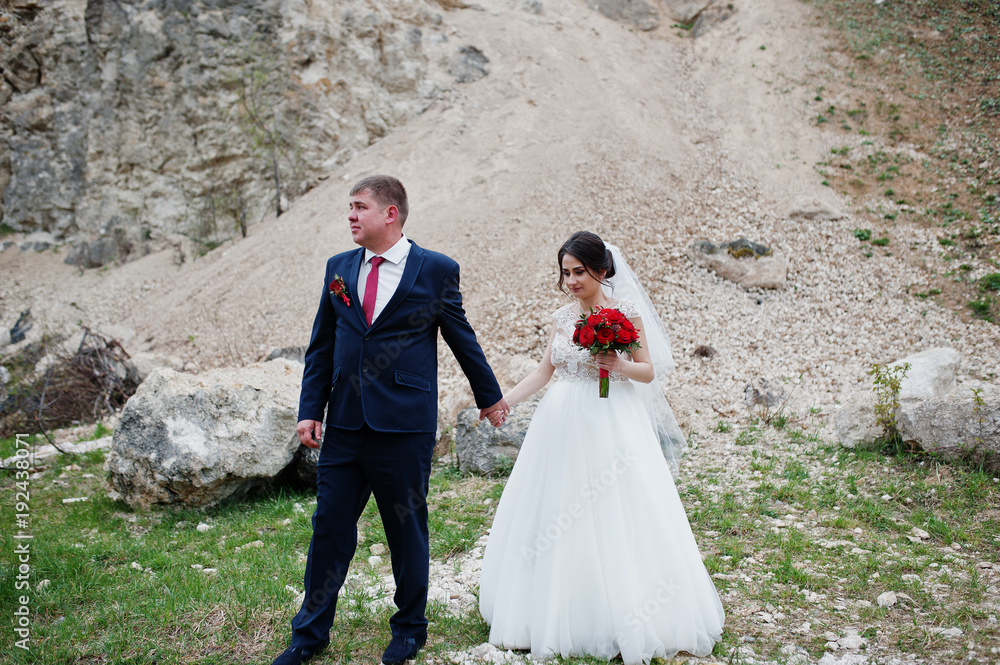Romantic newly married couple posing and walking in rocky countryside on their wedding day.