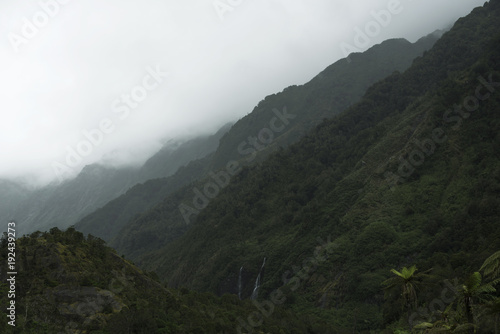 Paisaje de picos de montañas verdes con cielo blanco nublado