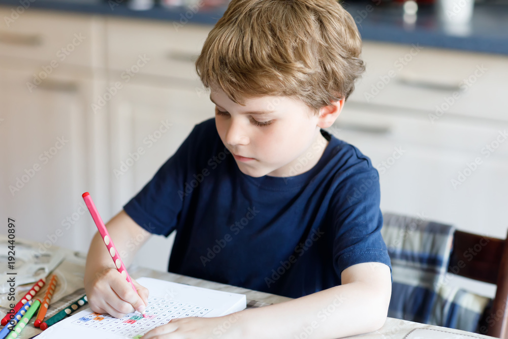 Happy smiling kid boy at home making homework writing letters with colorful pens Happy smiling kid boy at home making homework writing letters with colorful pens
