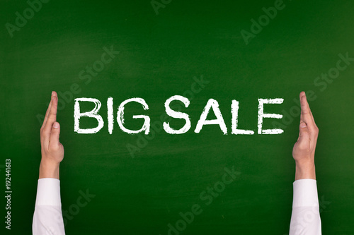 Hands Showing BIG SALE on Blackboard