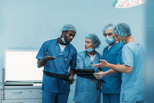 four multiethnic surgeons talking about patient x-ray in operating room photo