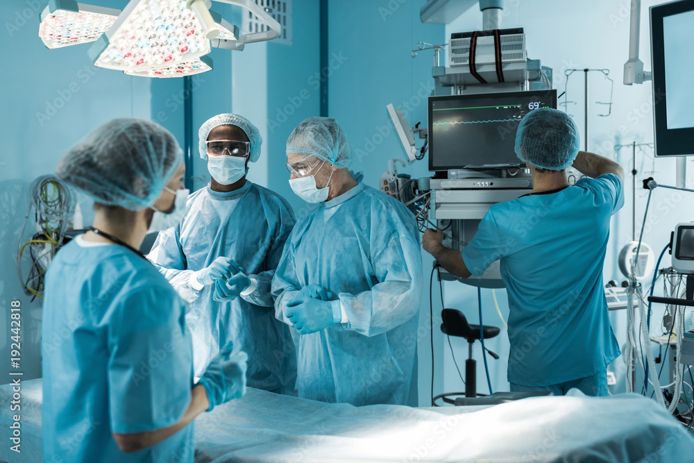 four multicultural doctors preparing for surgery four multicultural doctors preparing for surgery