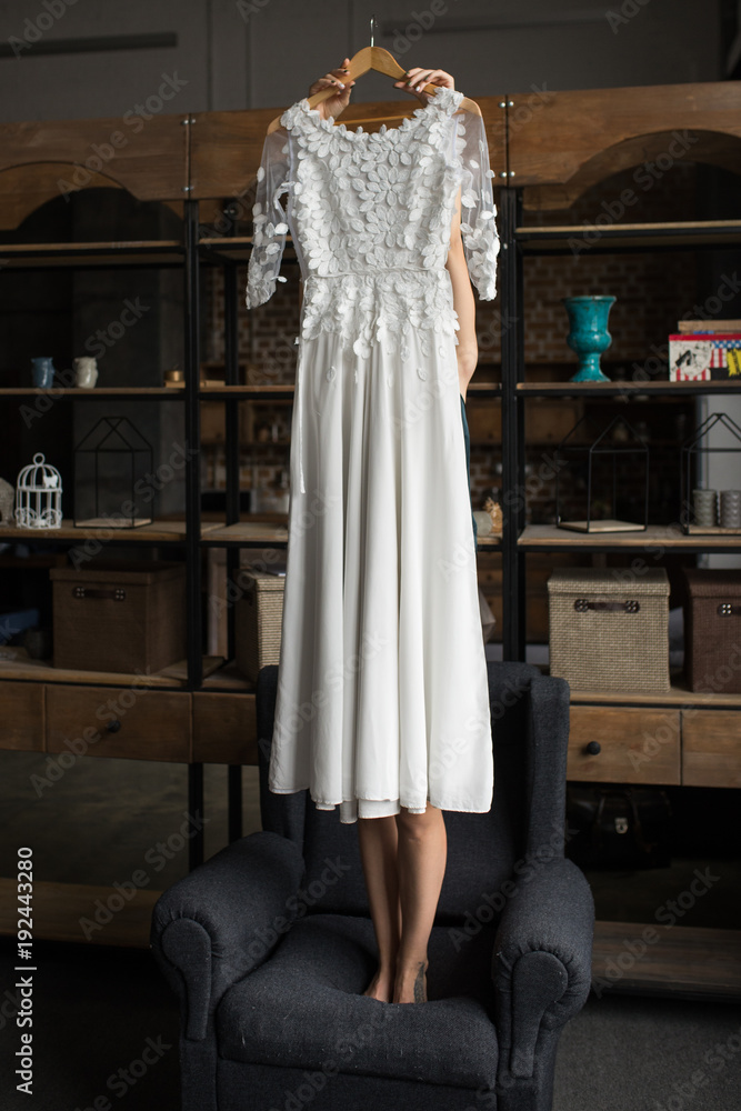 Bride holds a beautiful rustic wedding dress in her hands. Prepare for the wedding. Bride holds a beautiful rustic wedding dress in her hands. Prepare for the wedding.