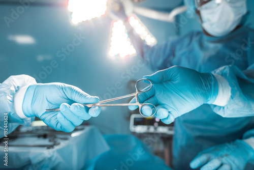 Foto cropped image of nurse passing medical scissors to surgeon