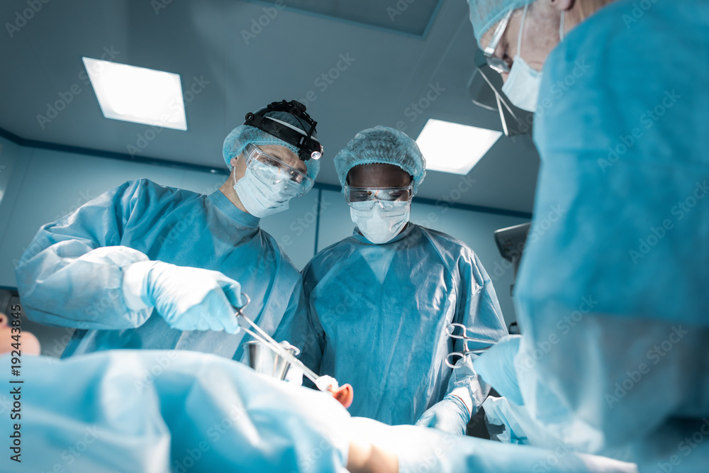 bottom view of multicultural surgeons and patient in operating room bottom view of multicultural surgeons and patient in operating room