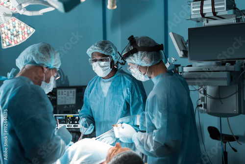 Obraz na płótnie multicultural surgeons operating patient in operating room