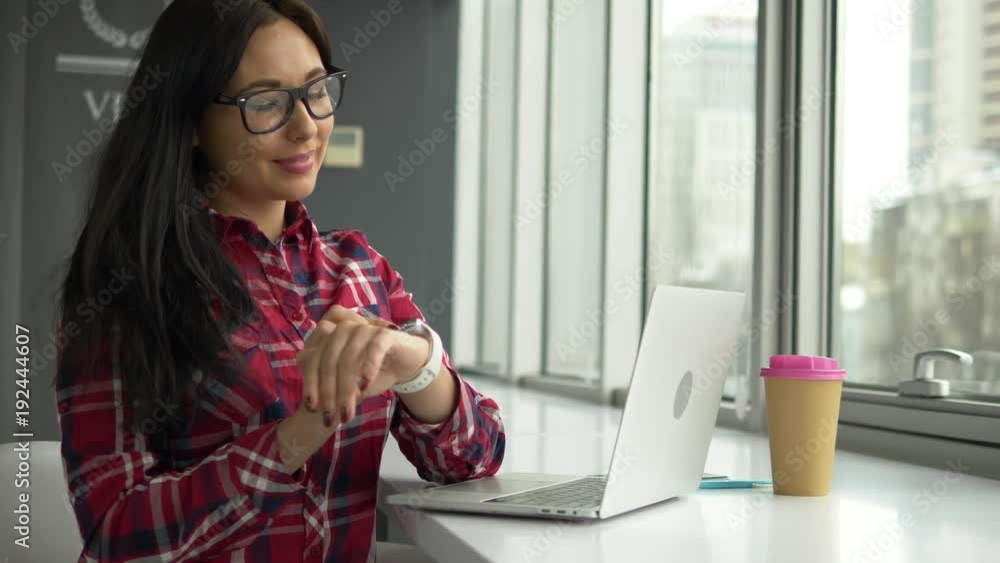Hipster mixed race woman using smartwatch and working on laptop pc in cafe. Hipster mixed race woman using smartwatch and working on laptop pc in cafe.