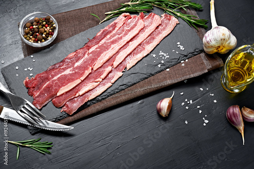 Canvas Print Bacon rashers with rosemary, garlic and olive oil isolated on black background
