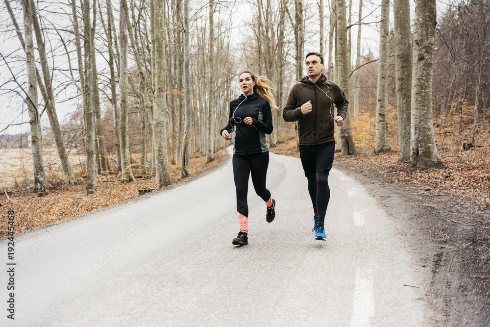 Man and woman running along rural road in Sodermanland, Sweden Man and woman running along rural road in Sodermanland, Sweden