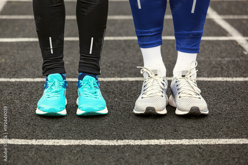 Front cropped view of two runners in running shoes.