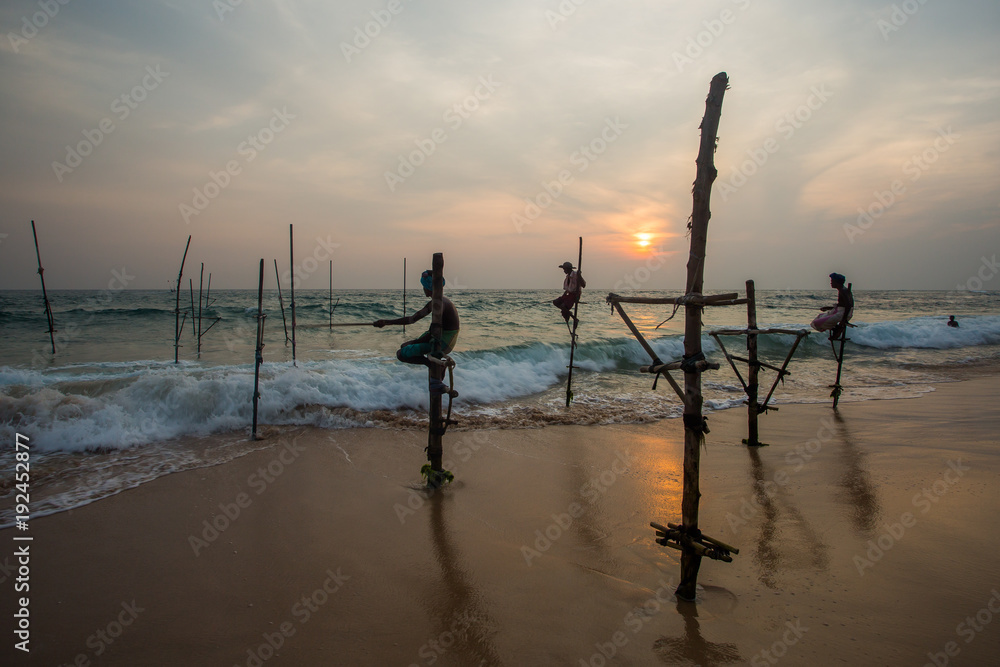  Silhouettes of the traditional Sri Lankan stilt fishermen on a stormy in Koggala, Sri Lanka. Stilt fishing is a method of fishing unique to the island country of Sri Lanka 

