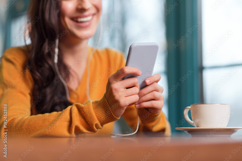 Advanced smartphone. Close up of tender young female hand hold phone while cup of tea standing on surface Advanced smartphone. Close up of tender young female hand hold phone while cup of tea standing on surface