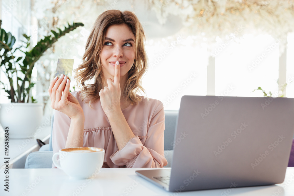 Portrait of a thoughtful young woman holding goldern credit card Portrait of a thoughtful young woman holding goldern credit card