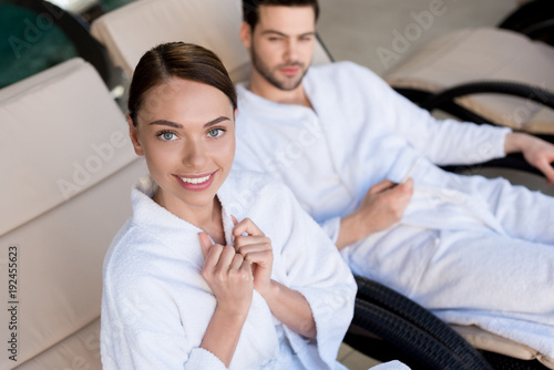 happy young couple in bathrobes resting together in spa center