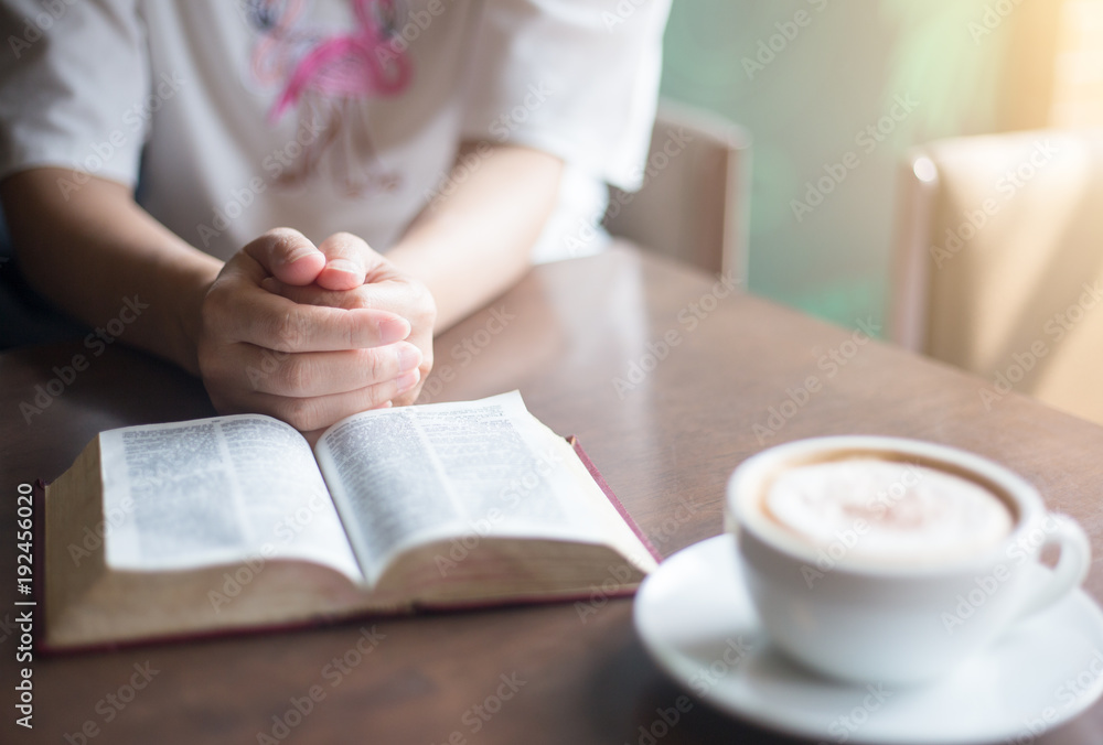woman hands on bible. she is reading and praying over bible over wooden table woman hands on bible. she is reading and praying over bible over wooden table