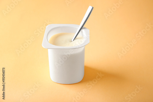 Plastic cup with yummy yogurt on color background