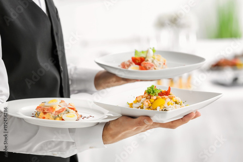 Waiter holding plates with dishes, closeup