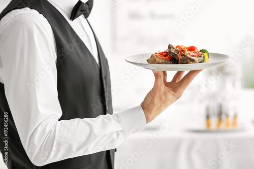 Waiter holding plate with meat and vegetables, closeup