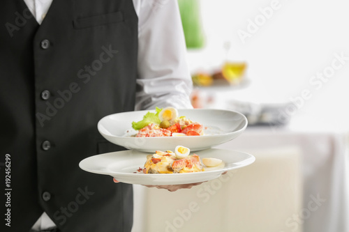 Waiter holding plates with dishes at banquet, closeup