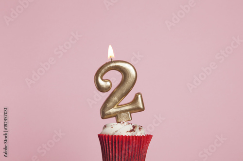 Canvas Print Number 2 gold candle in a cupcake against a pastel pink background