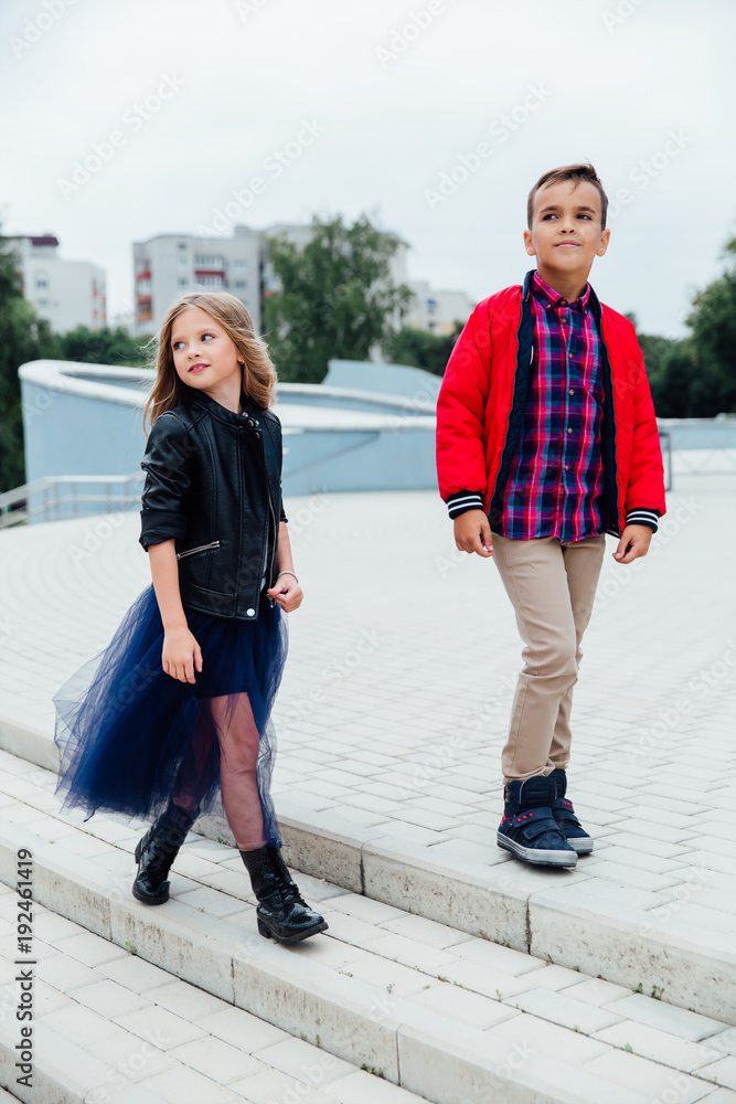 Fashion models children walk the stairs of the city streets. A boy and a girl, a blue skirt.