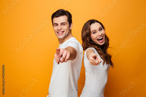 Portrait of a joyful young couple pointing fingers