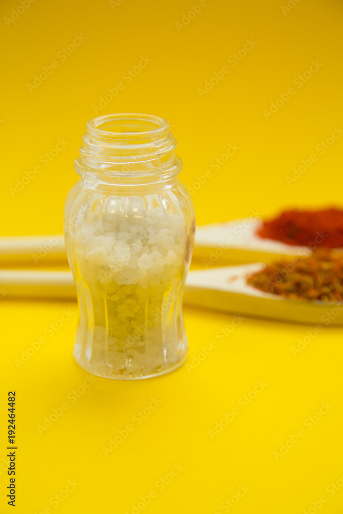 Wooden and plastic spoons with dry spices and fresh herbs on a yellow background with copy space, top view, close up Wooden and plastic spoons with dry spices and fresh herbs on a yellow background with copy space, top view, close up