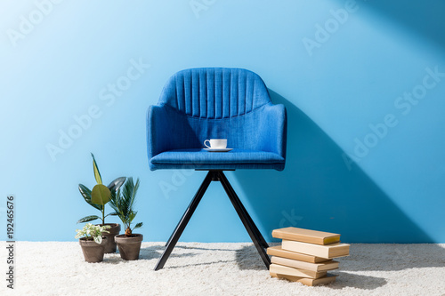 Картината върху платно comfy blue armchair with cup of coffee in front of blue wall