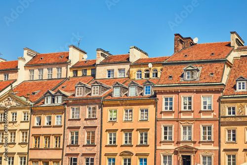 Facades of houses with windows and roofs against the blue sky on a clear sunny day in the old town in Warsaw, Poland