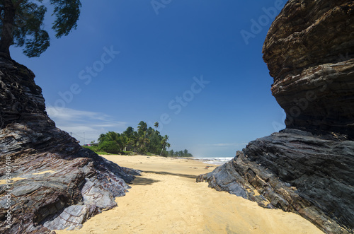 wild tropical island and rocky sea shore under bright sunny day and blue sky background.