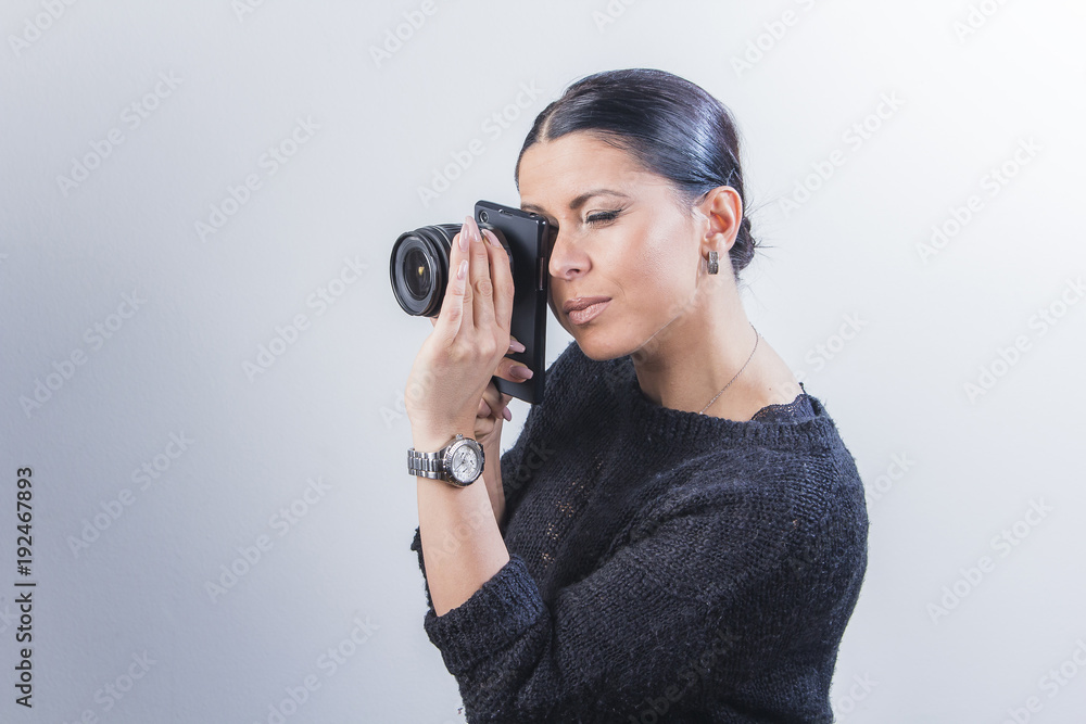 Young witty woman focusing her cell phone camera with a changeable lens Young witty woman focusing her cell phone camera with a changeable lens