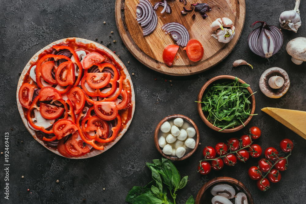 top view of uncooked pizza with different ingredients on concrete table top view of uncooked pizza with different ingredients on concrete table