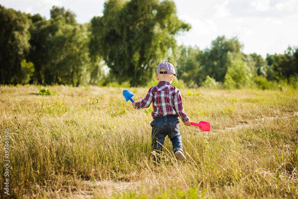 little boy walking along the road in summer little boy walking along the road in summer