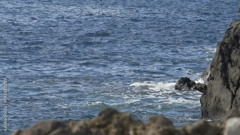Choppy waves of blue sea hitting rocks, cliffs emerging from water, slow motion Choppy waves of blue sea hitting rocks, cliffs emerging from water, slow motion