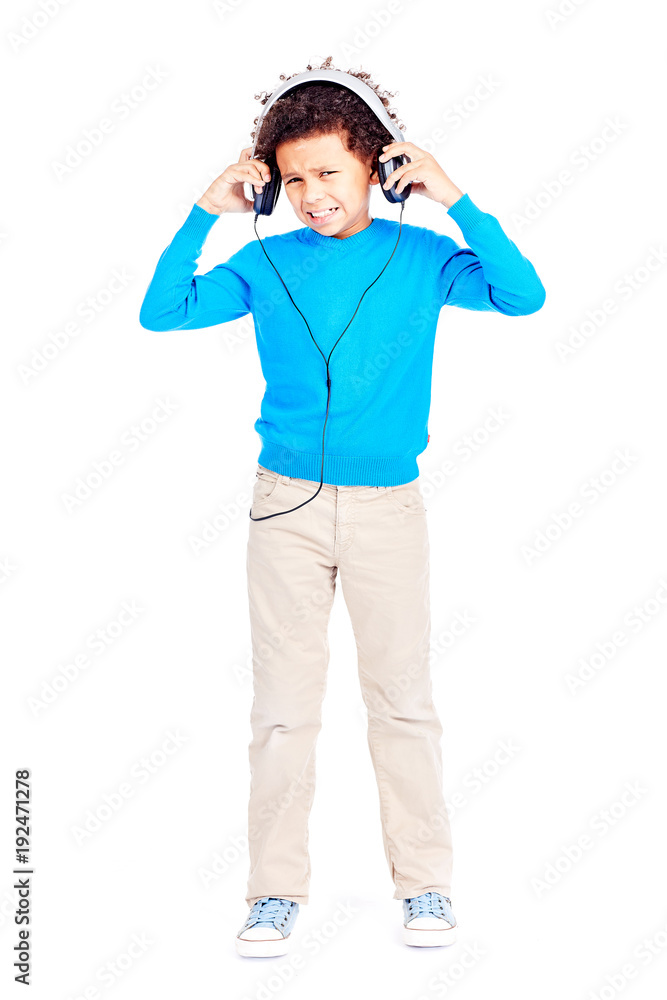 Portrait of cute curly-haired Latin American boy annoyed with music in his headphones Portrait of cute curly-haired Latin American boy annoyed with music in his headphones