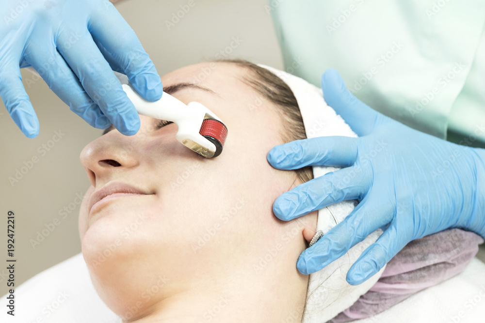 The woman undergoes the procedure of medical micro needle therapy with a modern medical instrument derma roller The woman undergoes the procedure of medical micro needle therapy with a modern medical instrument derma roller
