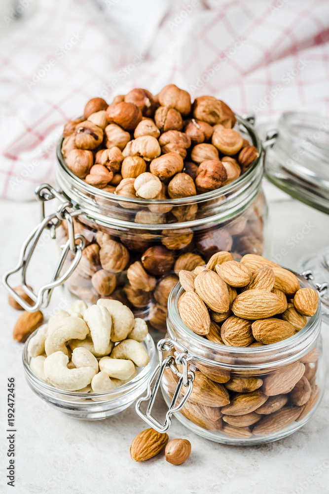 Nut mix in glass jars, walnuts, hazelnuts, almonds, cashew on white background. Selective focus, copy space. Nut mix in glass jars, walnuts, hazelnuts, almonds, cashew on white background. Selective focus, copy space.