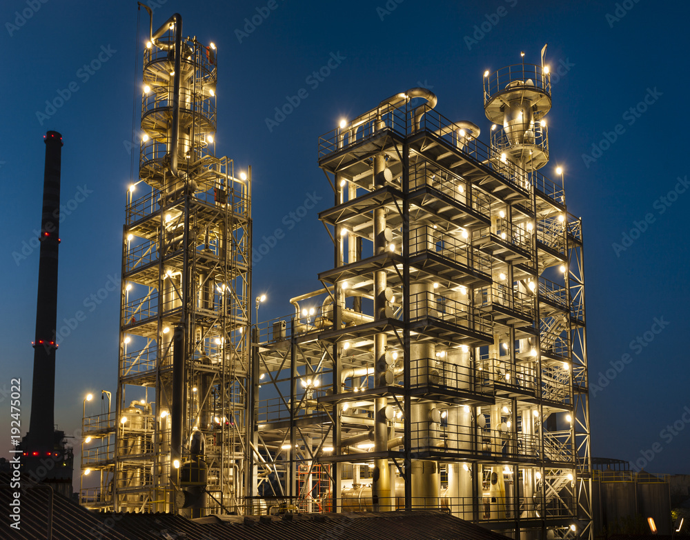 overall view of an oil refinery illuminated at night, pipelines and towers, heavy industry
