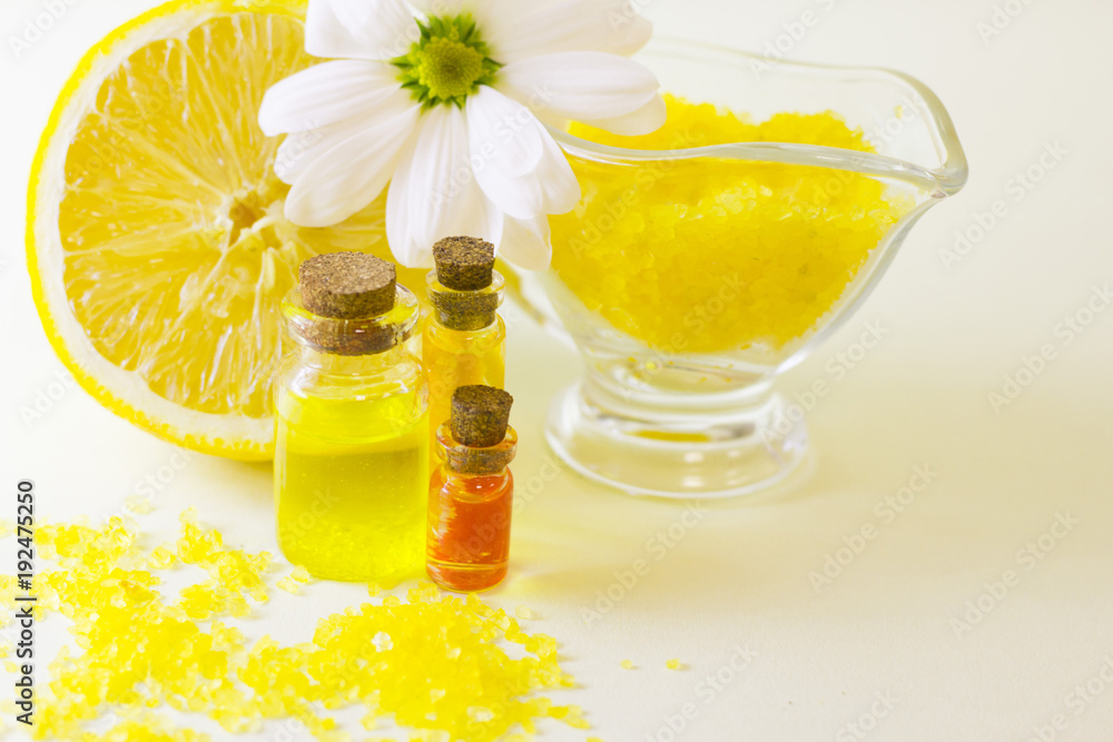 Fruit aromatherapy concept with essential oil in glass bottles, a bowl of bath sea salt, flowers and lemon, white background, close up Fruit aromatherapy concept with essential oil in glass bottles, a bowl of bath sea salt, flowers and lemon, white background, close up